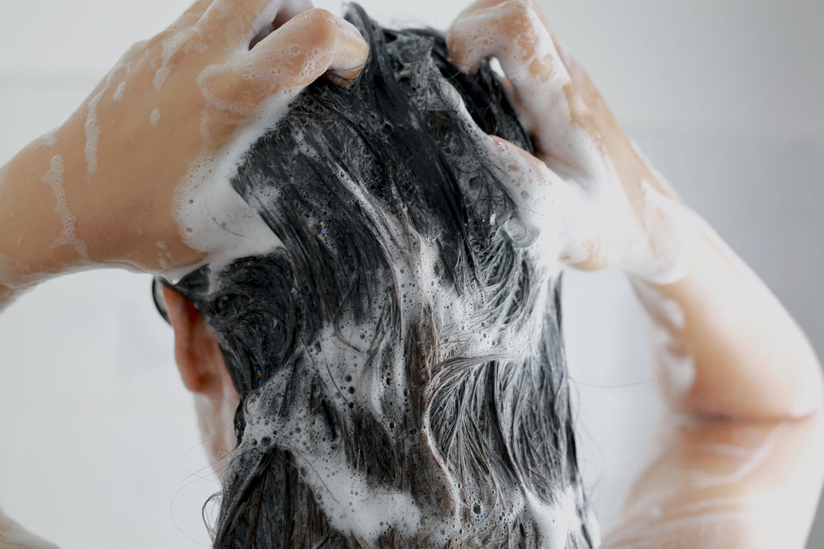 Close up of woman from behind washing soapy black hair