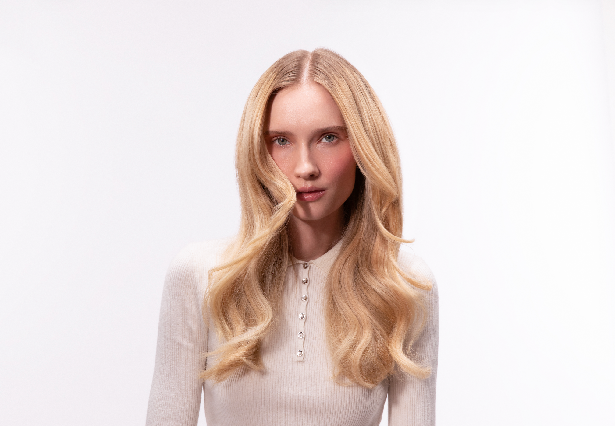 Woman wearing white high-neck top with healthy blow-dried blonde hair