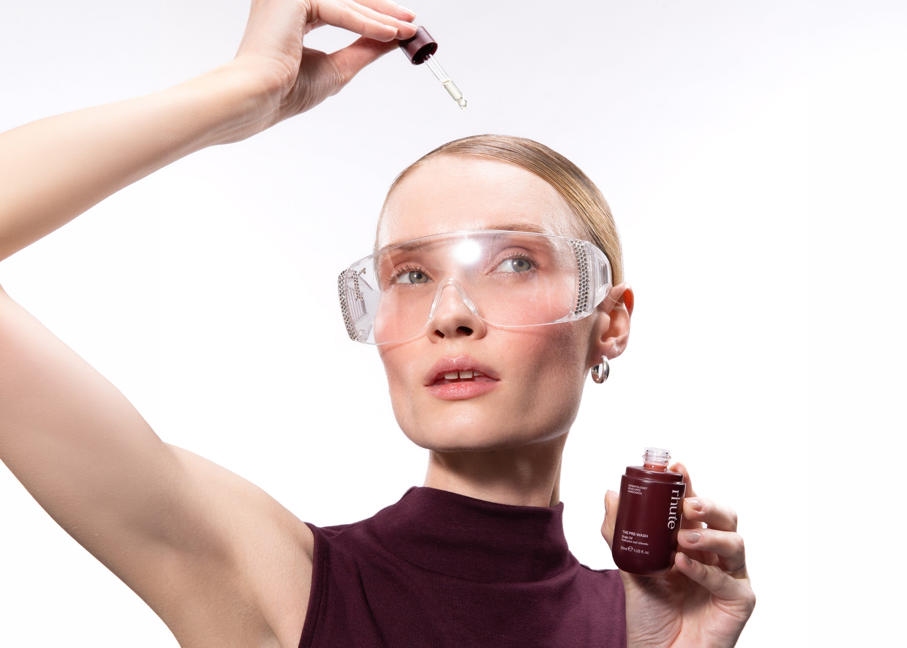 Woman with slicked back blonde hair applying rhute's Triple Density Complex Pre-Wash Scalp & Hair Oil