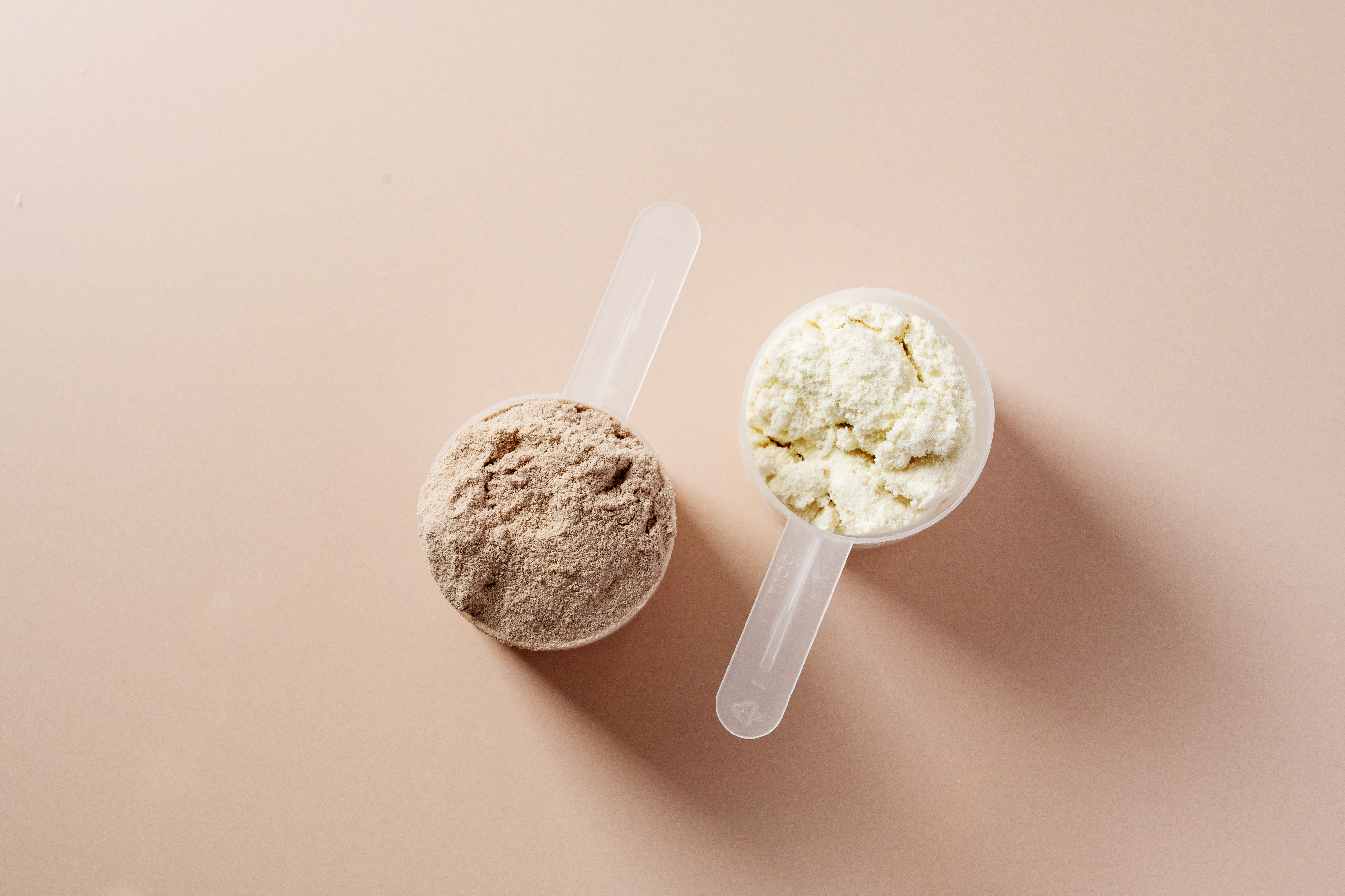 Two scoops of protein power on a light pink background
