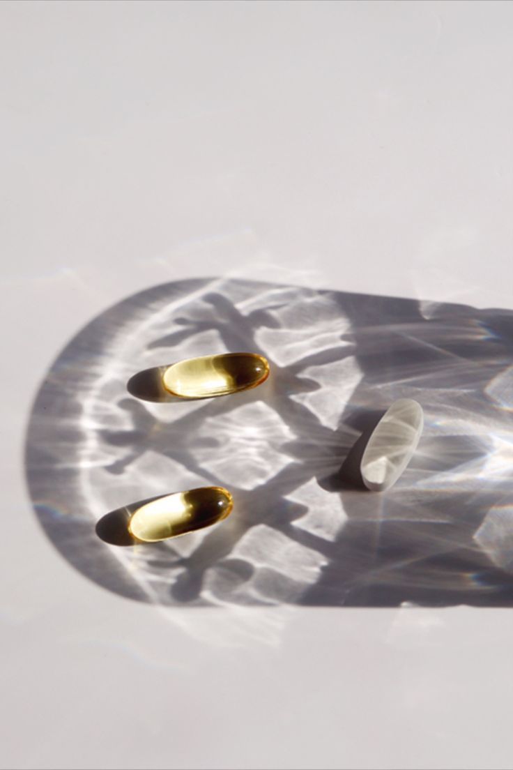 Close up of three supplements on a white surface with a shadow cast over them