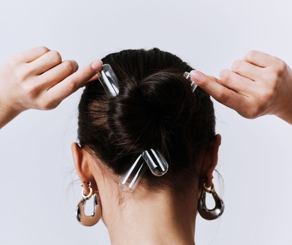 Person using hair clips to style their hair against a light background