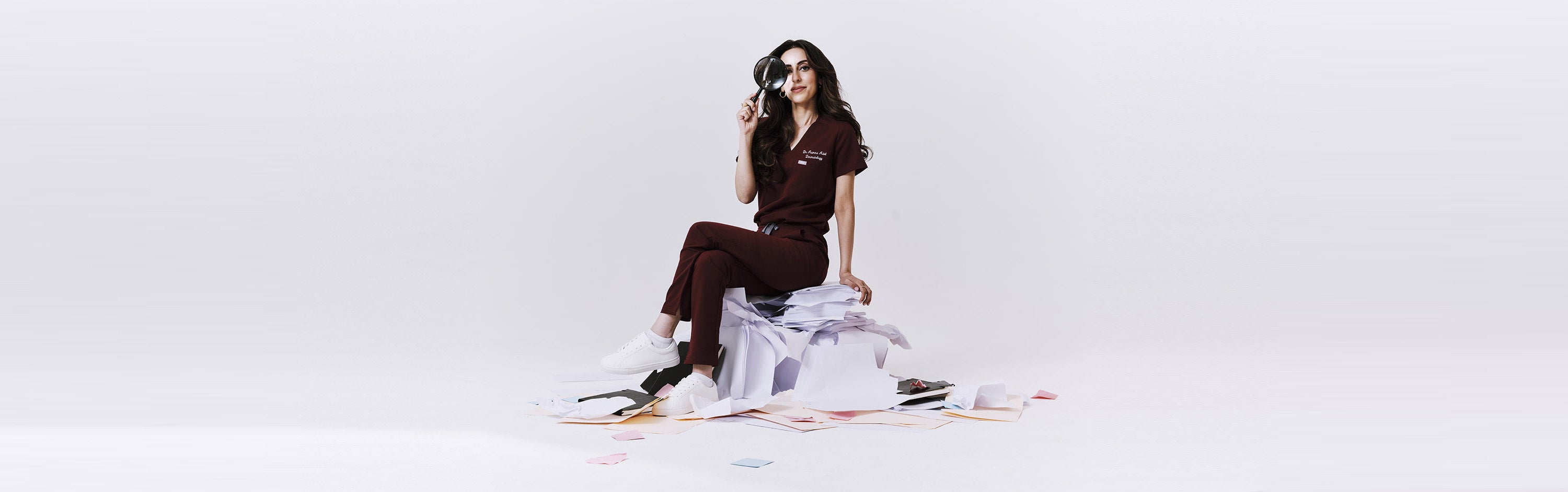 Woman sitting on a white stool with a white background