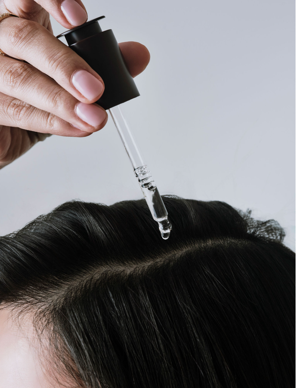 Person applying a dropper of hair serum