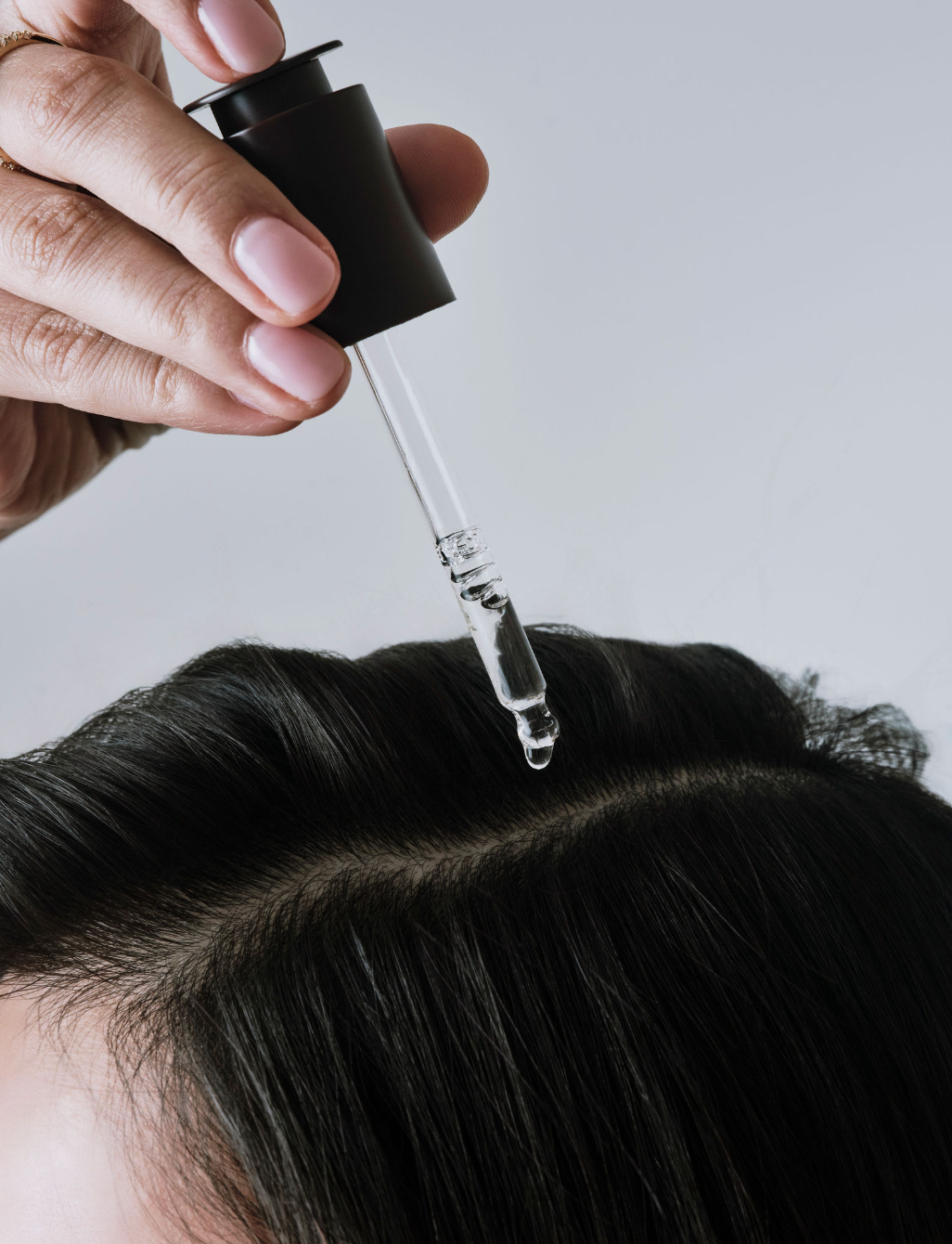 Person applying a dropper of hair serum