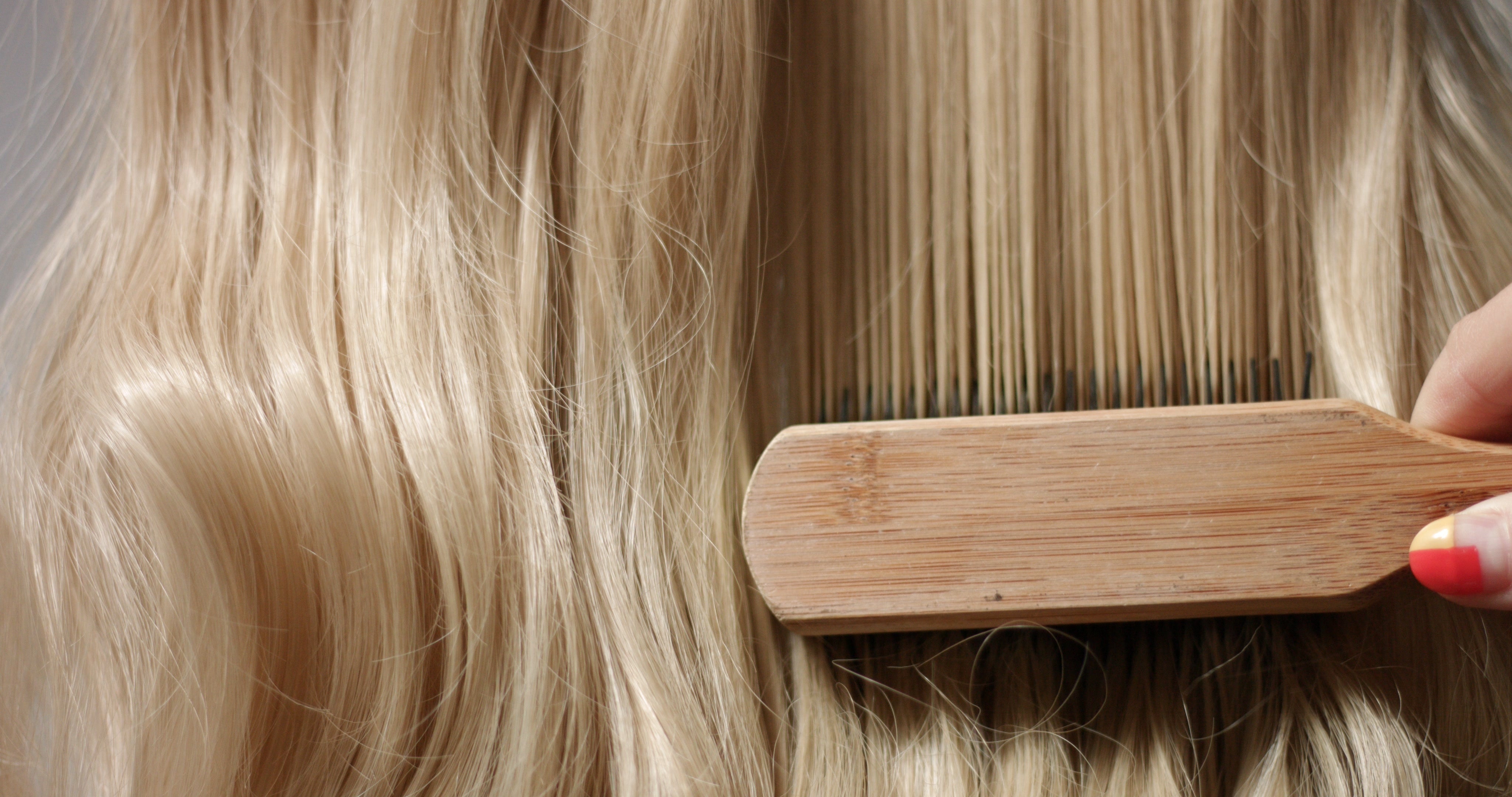 Close up of wooden brush combing through light blonde hair