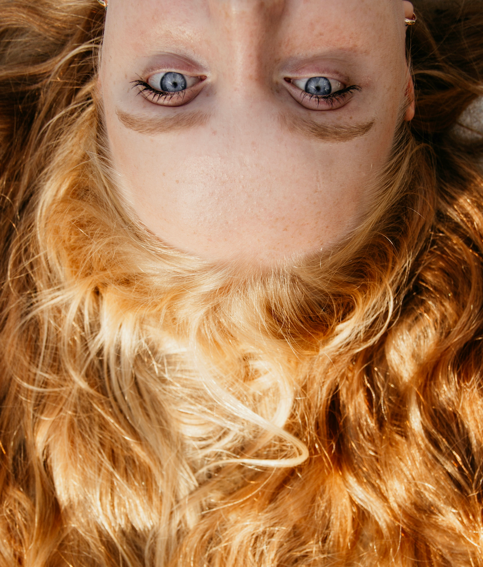 Woman with red hair lying down upside down from above