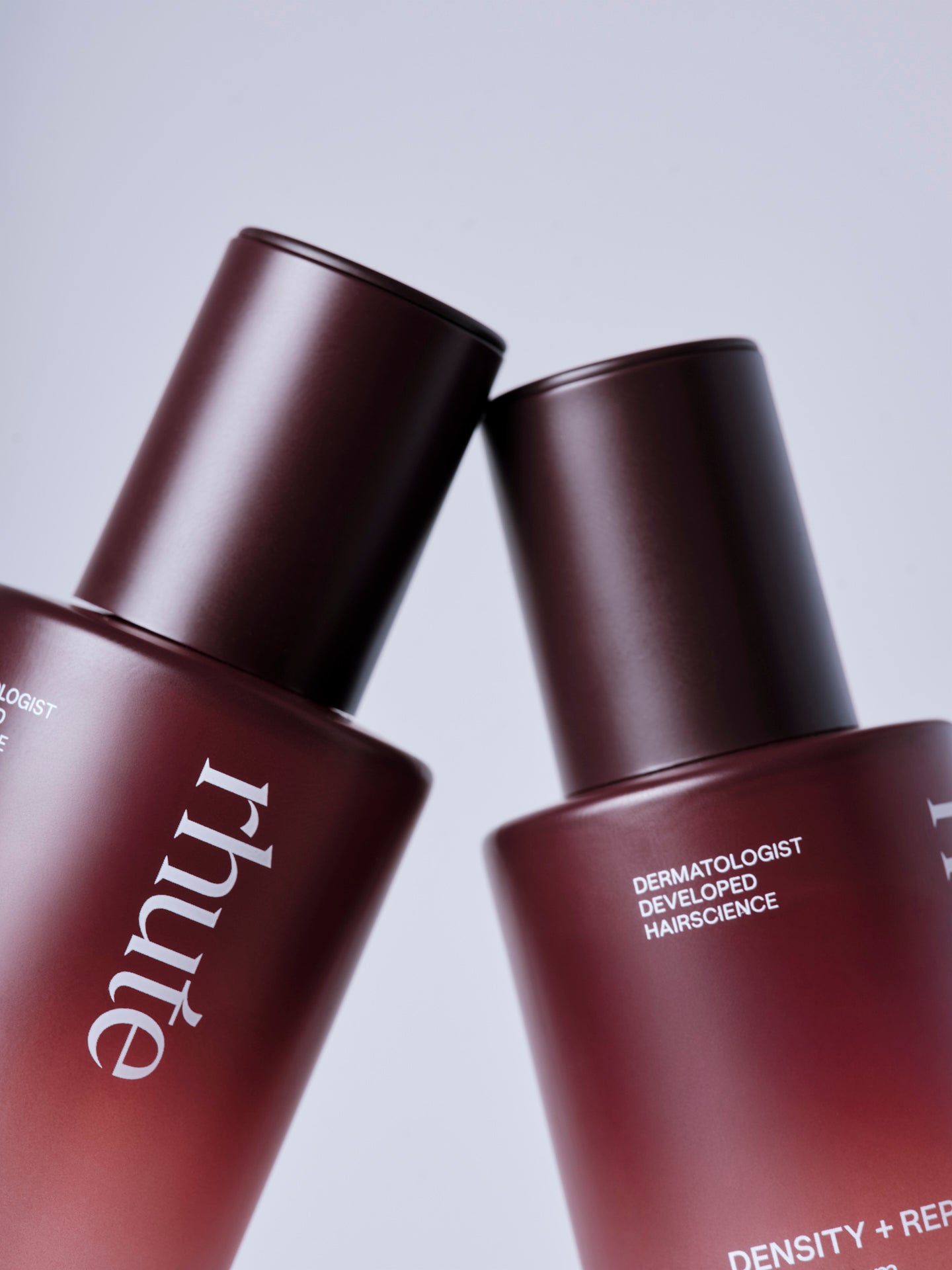 Close-up of two Rhute ‘Density + Repair’ bottles leaning together on a light background.